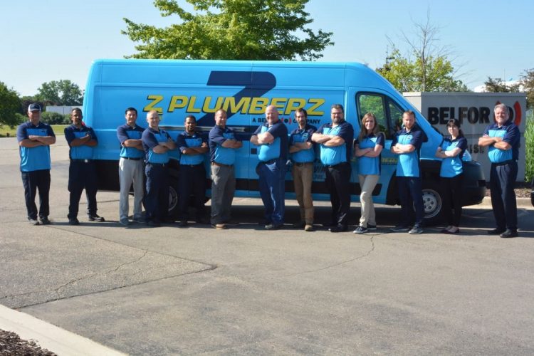 Team of plumbers standing in front of a van
