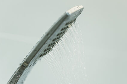 Water dripping out of modern shower head.