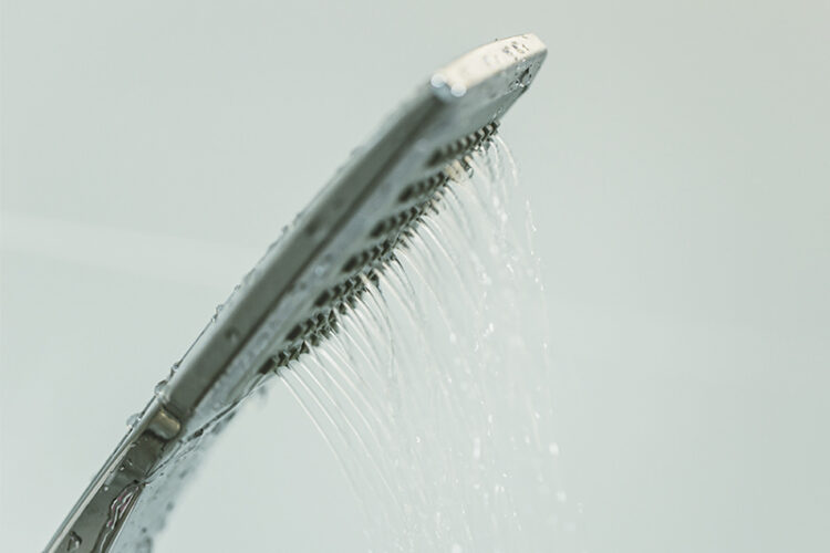 Water dripping out of modern shower head.