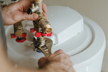 Man using wrench to tighten a fitting on a water heater.