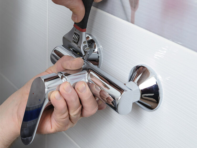 Plumber installing a shower handle.