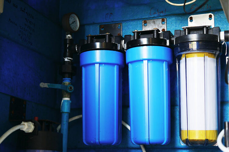 3 water filtration canisters mounted on a wall.