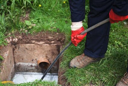 Plumber working on sewer line through access point.