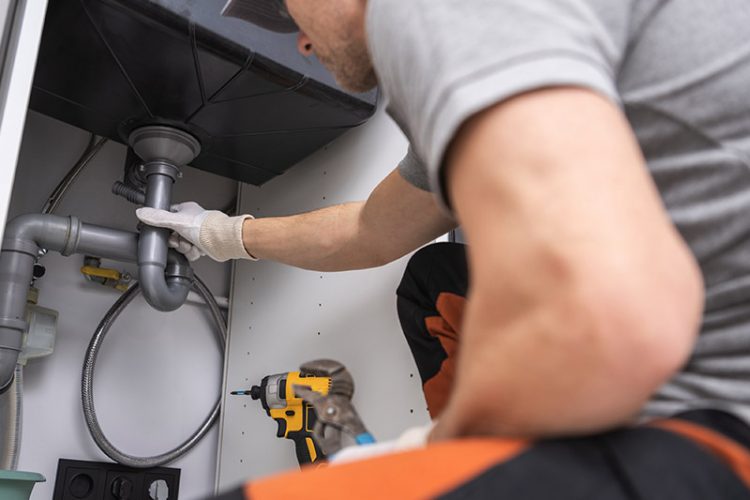 Plumber examining drain under a sink