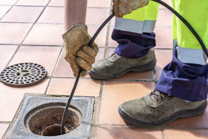 Plumber using tool to clear sewer line