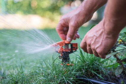 Man adjusting outdoor sprinkler head.