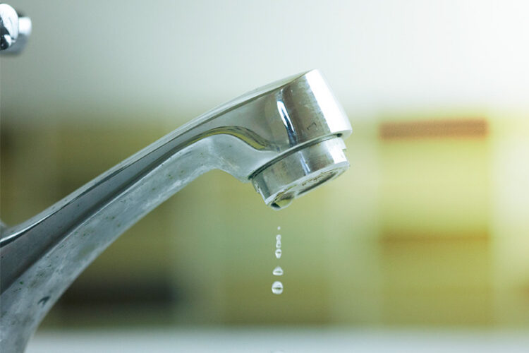 Water slowly dripping from a faucet.