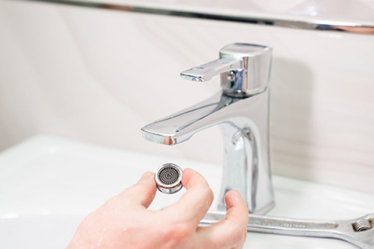Person replacing aerator on faucet.