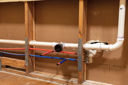New plumbing lines running through exposed kitchen wall.
