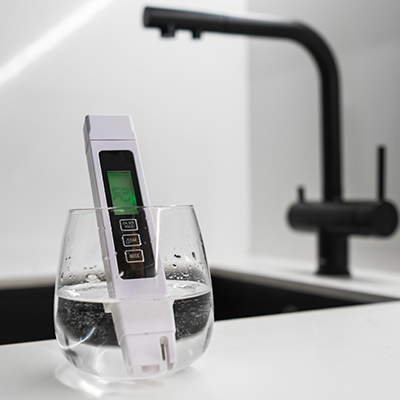 Glass of water with water testing tool sitting in it.