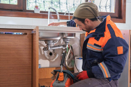 Plumber using equipment to clear a drain.