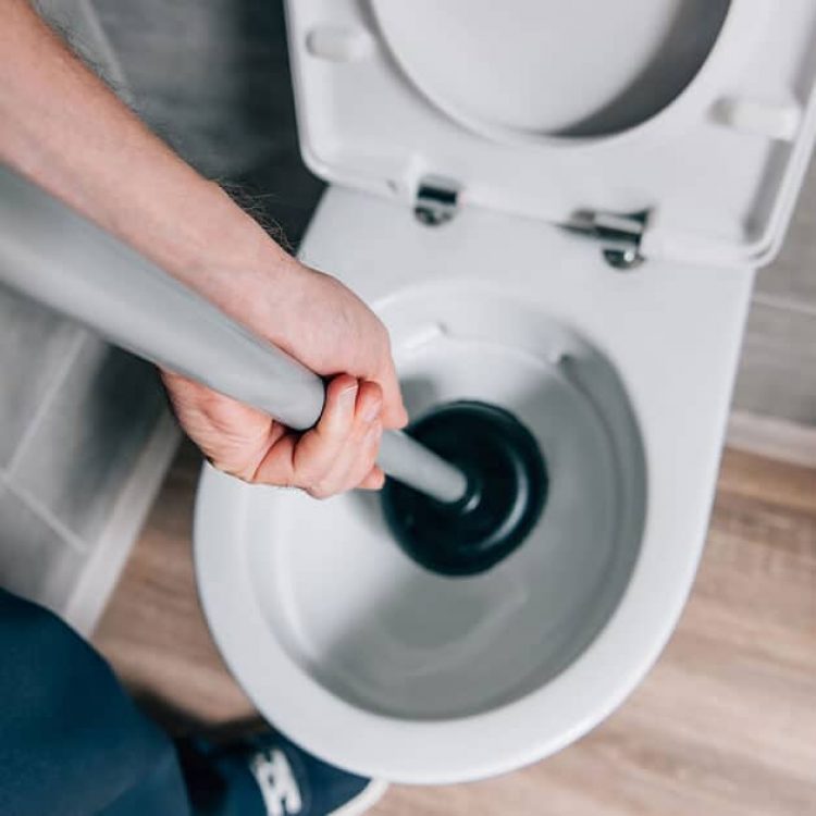 plumber unclogging a toilet