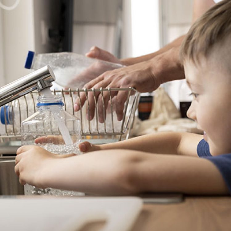 Young boy filling water bottle from tap