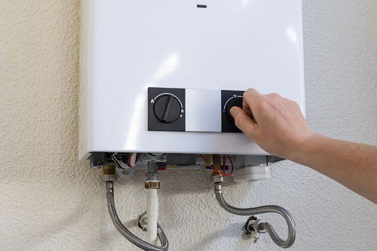 Man turning a knob on a tankless water heater.