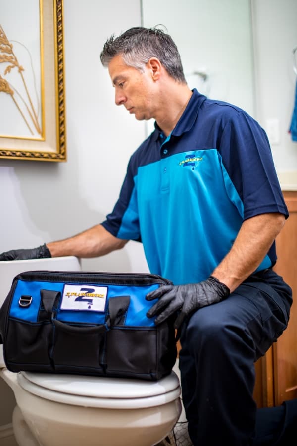 Worker kneeling in front of toilet with tools