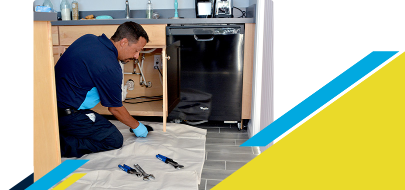 Kneeling Z PLUMBERZ of Central Long Island technician inspecting a dishwasher